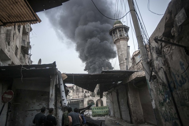 Rebel fighters watch as smoke rises after Syrian government forces fired an artillery round at a rebel position in the Jedida district of Aleppo on Nov. 04, 2012.
