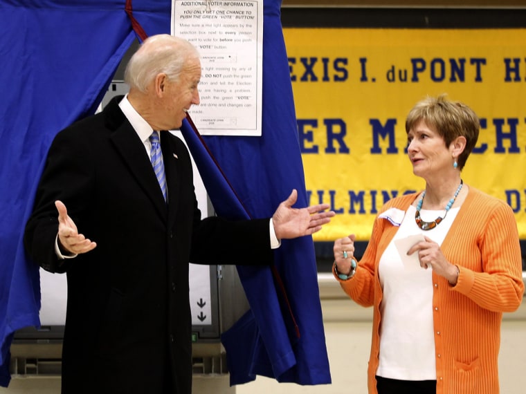 Joe Biden reacts to a poll worker as he emerges from the voting booth.