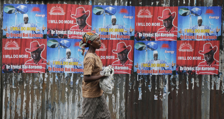 A woman walks past campaign posters for incumbent President Ernest Bai Koroma in Freetown, Sierra Leone, Nov. 15, 2012. Ten years after the end of a devastating civil war, Sierra Leone will go to the polls on Saturday to choose between incumbent Koroma and opposition leader Julius Maada Bio.