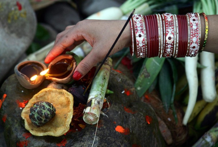 An Indian devotee lights earthen lamps as she performs rituals in front of the setting sun at the sacred Tawi river during the Chhath festival in Jammu, the winter capital of Kashmir, India, on Nov. 19.