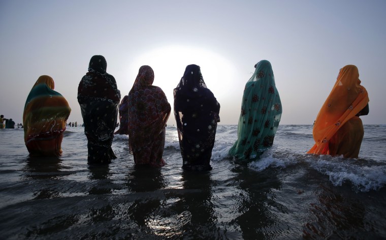 Hindu devotees pray while standing in the waters of the Arabian Sea as they worship the sun god during the Hindu religious festival