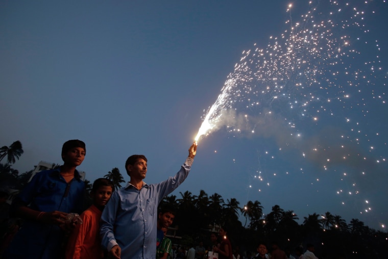 A Hindu devotee holds a firework in his hand as he worships the sun god during the Hindu religious festival