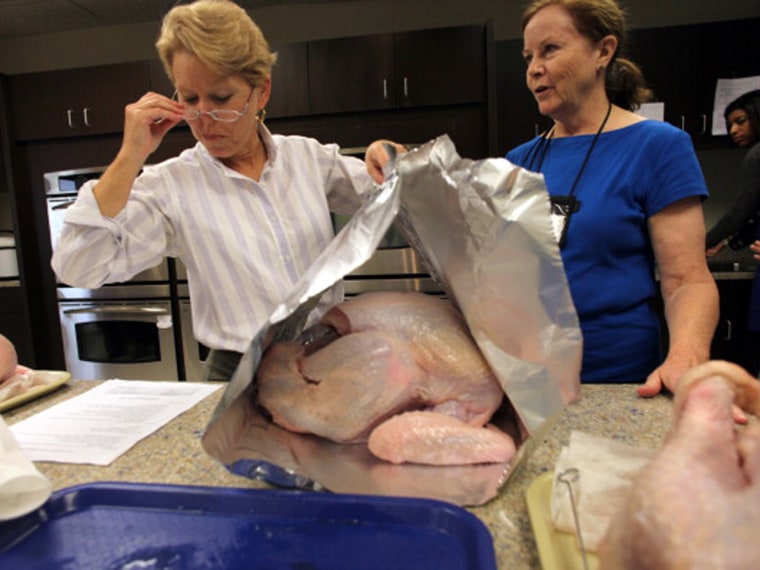 Barbra Robinson, left, looks over instructions as she wraps a turkey in foil under the watch of supervisor Alice Coffey during training for Butterball Turkey Talk-Line employees in 2010 in Naperville, Ill. Butterball expects to answer the questions of 1 million cooks this holiday season.