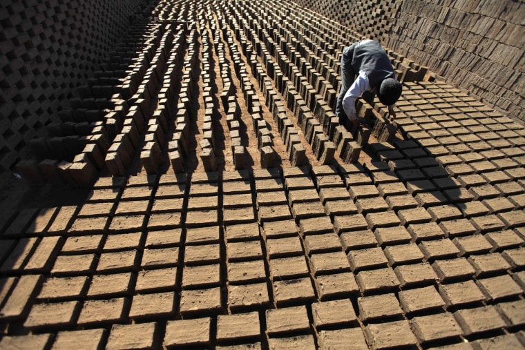 A boy arranges dried mud blocks at a traditional brick manufacturing site in San'a, Yemen, Nov. 20, 2012. The bricks are made from clay and straw and widely used in the construction of houses due to its low cost.