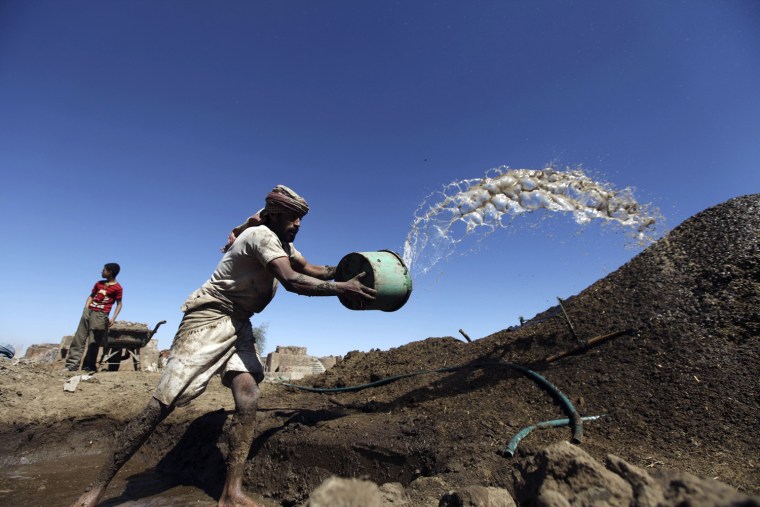 A worker adds water to clay mixed with straw at a traditional brick-manufacturing site in San'a, Yemen, Nov. 20.