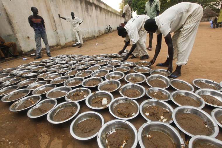 Inmates line up bowls of food for dinner in Rumbek Central Prison in Rumbek, South Sudan, Oct. 25.