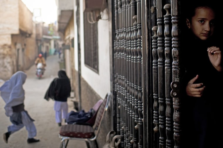 A young girl peeks out from the barred entrance to her school waiting for her fellow students to arrive at Khushal School for Girls in Mingora, Swat Valley Pakistan. Photo taken Nov. 15.