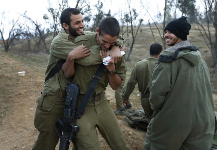 An Israeli soldier, left, hugs a comrade, center, to congratulate him for his birthday at a staging area in southern Israel near the Gaza Strip border on Nov. 22, 2012. A cease-fire agreement between Israel and the Gaza Strip's Hamas rulers took effect Wednesday night, bringing an end to eight days of the fiercest fighting in years.