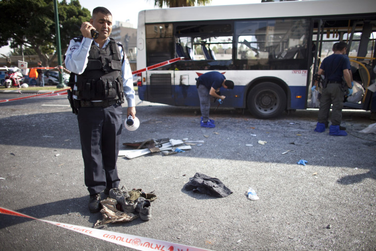 An Israeli policeman stands above shoes and clothes from a victim at the scene of an explosion on a bus in central Tel Aviv, Israel, Nov. 21.