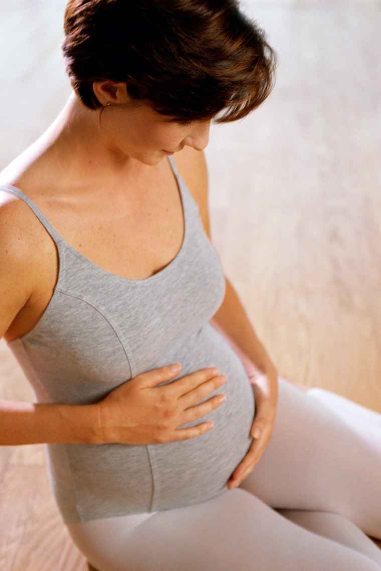 Pregnant woman in leotard, holding stomach; fitness; photodisc; baby weight; getty Images msnbc stock photography pregnant pregnancy