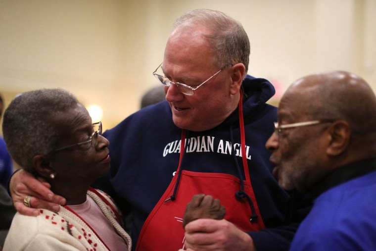 Cardinal Timothy Dolan, Archbishop of New York, speaks with people waiting for free Thanksgiving groceries at the Lt. Joseph P. Kennedy Jr. Memorial Community Center in Harlem on Tuesday.