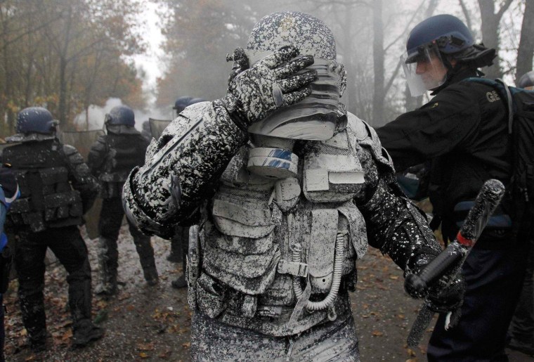 A French riot gendarme reacts after being covered with lime during clashes with demonstrators during an evacuation operation on land that will become the new airport in Notre-Dame-des-Landes, western France, on November 23, 2012.