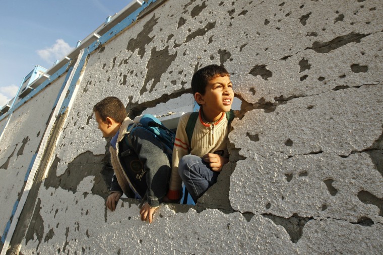 Palestinian schoolboys look through a hole at their damaged school, run by the United Nations, in Gaza City, on Nov. 24.