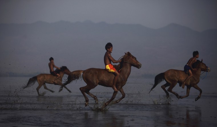 Endiansyah Mohammad, center, warms up his horse on Kalaki beach.
