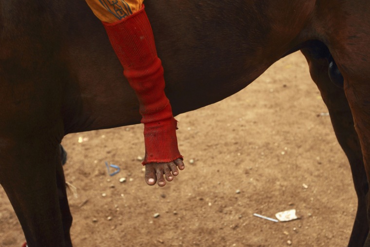 The foot of child jockey is seen as he sits on his horse at Panda racetrack.