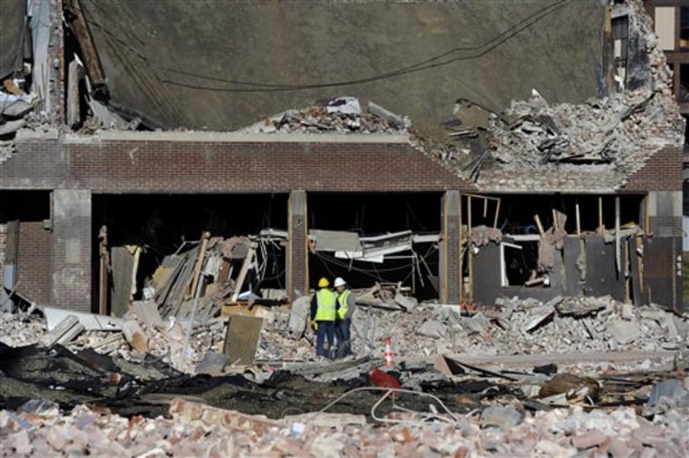Inspectors stand in debris Saturday at the site of a gas explosion that leveled a strip club in Springfield, Mass., on Friday evening.
