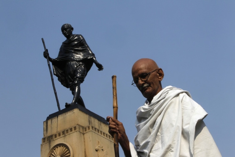 Mahesh Chaturvedi poses for a photo in front of a statue of Gandhi in the old quarters of New Delhi on October 25, 2012.