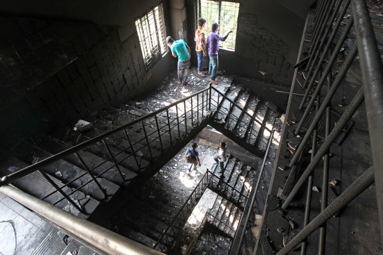 Bangladeshi garment workers walk on the burned stairs of the nine-story Tazreen Fashion plant in Savar, about 30 kilometers north of Dhaka on Nov. 26. The factory was the scene of a fire on Saturday that killed at least 112 people.