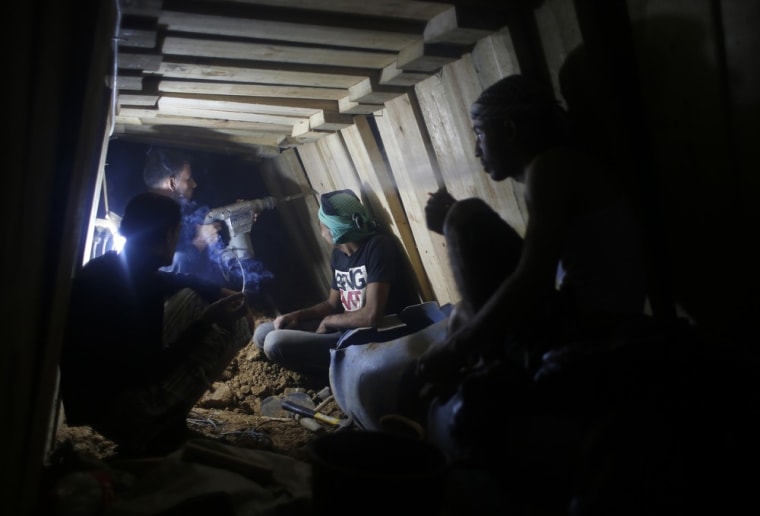Palestinians rest as a worker repairs a smuggling tunnel dug beneath the Egyptian-Gaza border in Rafah, in the southern Gaza Strip on Monday. Knee-deep in craters carved out by Israeli airstrikes, Palestinians wielded shovels and planks to reopen tunnels used to smuggle in goods from Egypt to Gaza, as international aid agencies raced to replenish Gaza's supplies.