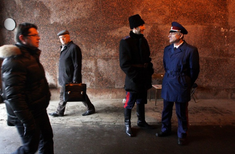 Two Cossacks, right, watch pedestrians passing by as they patrol Belorussky railway station in downtown Moscow on Nov. 27, 2012.