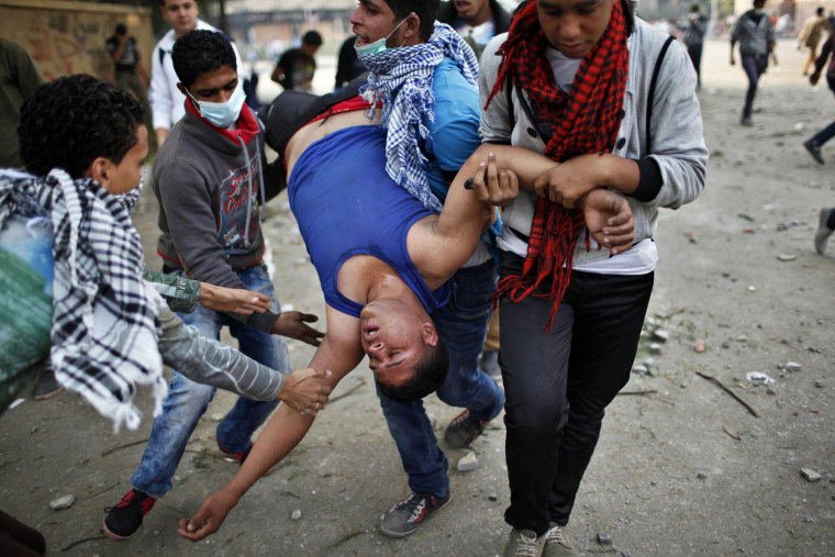 Anti-Morsi protesters carry a wounded man away from tear gas during clashes with riot police at Tahrir square in Cairo, Nov. 27.