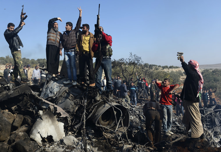 Syrian rebels celebrate on top of the remains of a Syrian government fighter jet which was shot down at Daret Ezza, on the border between the provinces of Idlib and Aleppo, on Nov. 28. Syrian rebels captured a pilot manning the fighter jet downed over Daret Ezza in the northern province of Aleppo, witnesses told an AFP reporter in the town.