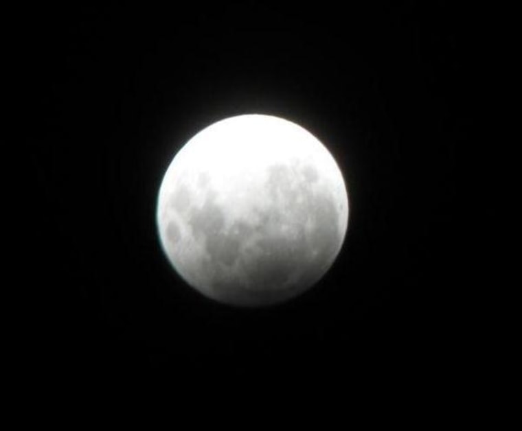 Earth's shadow slightly darkens the moon over Chiba City in Japan.