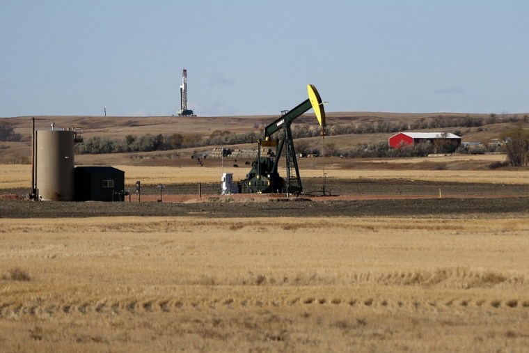 An oil-drilling rig and an oil pump jack are seen Oct. 20 outside Watford, N.D.