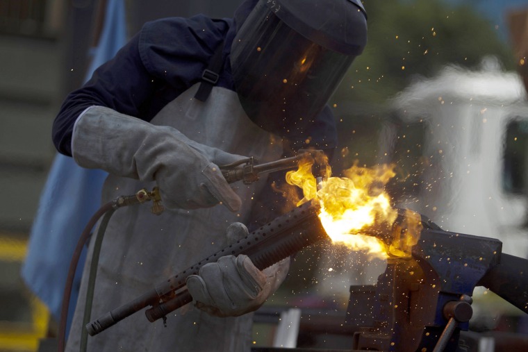 A worker destroys a shotgun during a public destruction of confiscated weapons in Lara, Venezuela, Nov. 30.