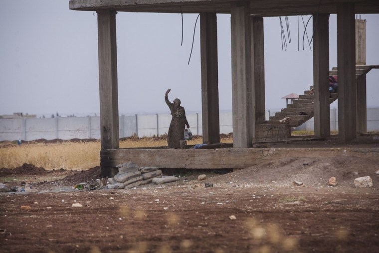 A displaced Syrian woman is seen in a building still under construction in an improvised refugee camp at the border with Turkey, near Azaz village, Syria, Sept. 30, 2012.