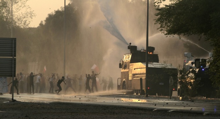Bahraini anti-government protesters throwing stones and petrol bombs and carrying national flags clash with riot police firing tear gas and water cannons on the outskirts of the capital of Manama, Bahrain, on Tuesday, Oct. 2, 2012.