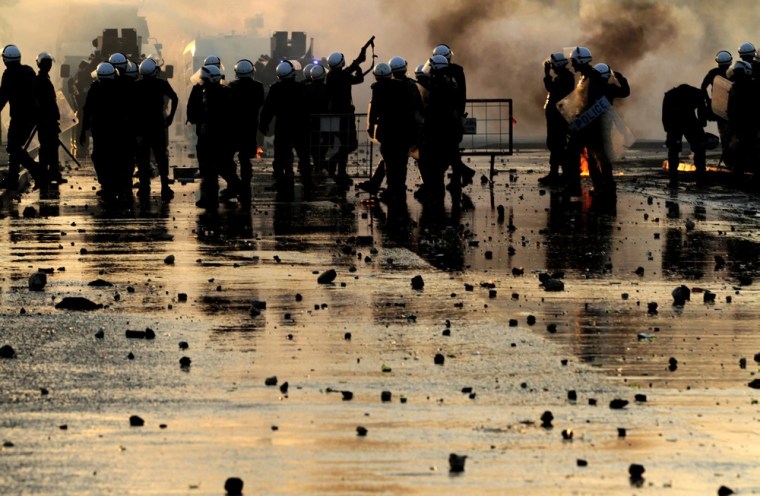 Riot police stand on a street sprayed wet by water cannons and fire tear gas at anti-government protesters throwing stones and petrol bombs on the outskirts of the capital of Manama, Bahrain, on Tuesday, Oct. 2, 2012.