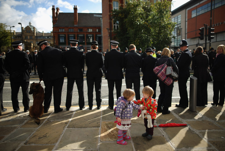 Children play as police officers line the streets ahead of the funeral of police Constable Nicola Hughes at Manchester Cathedral on Oct. 3.