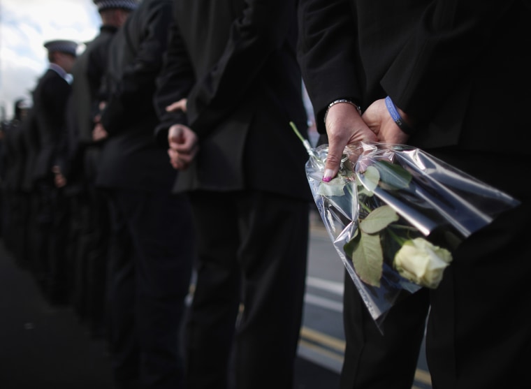 A police woman holds flowers as she lines the route for the funeral cortege of police Constable Nicola Hughes at Manchester Cathedral on Oct. 3.