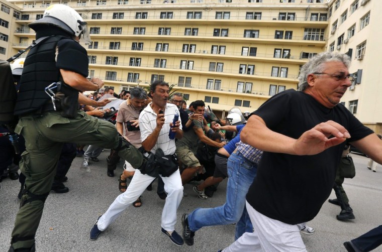 A riot policeman kicks protesters trying to escape arrest during a demonstration in the courtyard of the Defence Ministry in Athens on October 4, 2012.