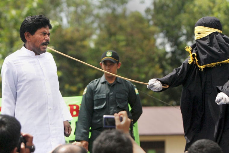 A Sharia law official whips a man convicted of gambling with a rattan cane during a public caning in Jantho, Aceh province, Indonesia, Friday, Oct. 1, 2010. A version of Islamic law was introduced in the province in 2009 as part of negotiations to end the 29-year war between separatist rebels and the military. The law bans gambling, drinking alcohol and makes it compulsory for women to wear headscarves.
