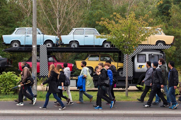 Refugees and supporters pass vintage East German Trabant cars during their protest march in the town of Werder, near Potsdam on October 4, 2012.