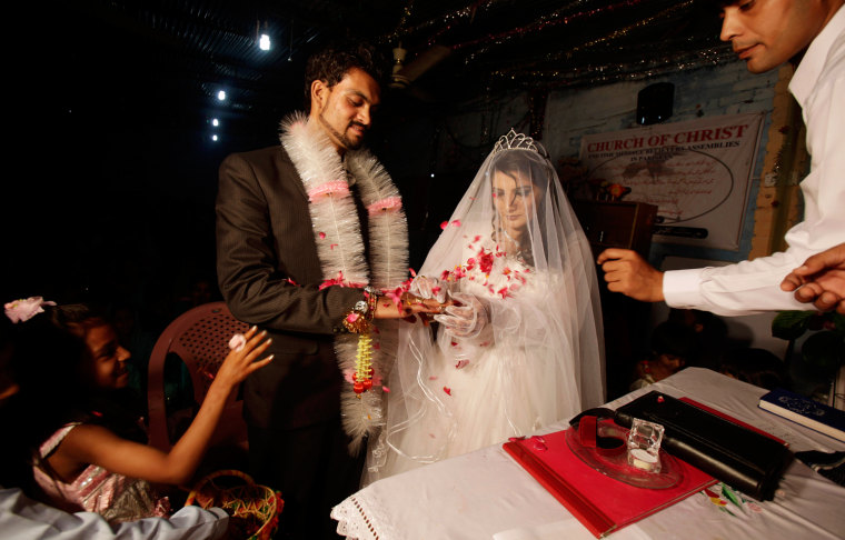 A Pakistani girl, bottom left, throws flowers on groom Phaloos Sohtra, 22, and his bride Shabana Gill, 20, as they exchange rings during their wedding in a church in a Christian neighborhood in Islamabad, Pakistan, on Oct. 5.