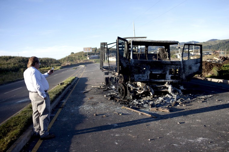 A man photographs a burned truck after the clashes where six peasants were killed on Thursday, when soldiers and police suppressed a peaceful demonstration in Totonicapan, Guatemala, Oct. 5.