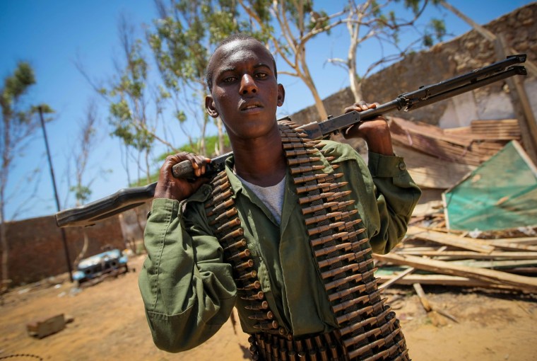 A fighter of the pro-governmnet Ras Kimboni Brigade stands with a belt-fed machine gun inside the former compound housing the offices of the United Nations High Commission for Refugees (UNHCR) during a combat engineering team's sweep for unexploded ordnance in Kismayu on Oct. 5.