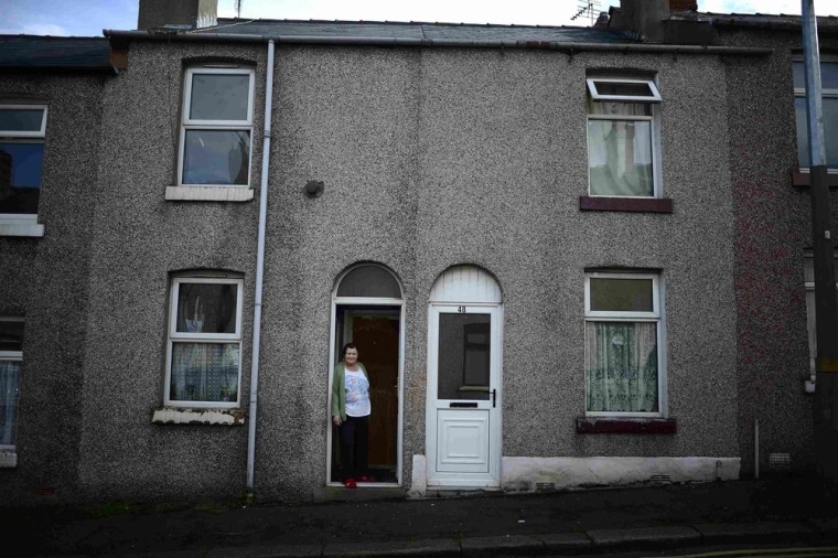 Jennie Iveson poses outside her terraced home in Barrow-in-Furness. Her distant cousin Mitt Romney is one of the wealthiest Americans ever to run for the White House. Today, Washington's backrooms of power and intrigue are as far removed from the daily grind of his distant kin in Lancashire as one can imagine.