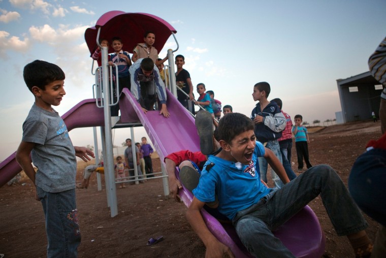Syrian refugee children play on slide put up for them in a camp at the Syrian-Turkish border near Azaz, Syria, Oct. 7, 2012. The makeshift refugee camp is reported to be growing daily, housing several thousand refugees under poor sanitary conditions and under the control of the Free Syrian Army.