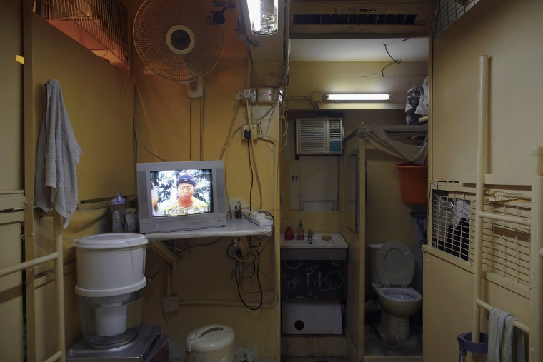 A movie is shown on a television in a common area between wooden boxes where people live in Hong Kong, October 9, 2012.