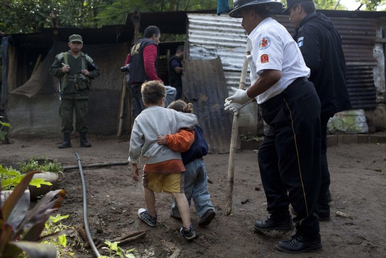 Carlos Daniel Gonzalez holds his sister Izabel as they are accompanied by authorities after unknown gunmen killed their parents and other relatives in Villa Canales, Guatemala, on Oct. 9.