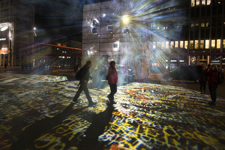 People walk through a light installation at the Potsdamer Platz during a rehearsal of the ninth Festival Of Lights in Berlin.