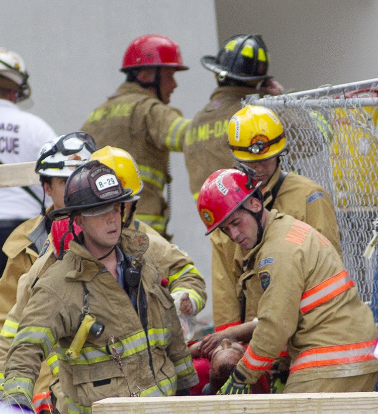Firefighters remove a victim from the rubble after a section of a parking garage under construction at Miami-Dade College campus collapsed in Doral, Fla., Oct. 10, 2012.
