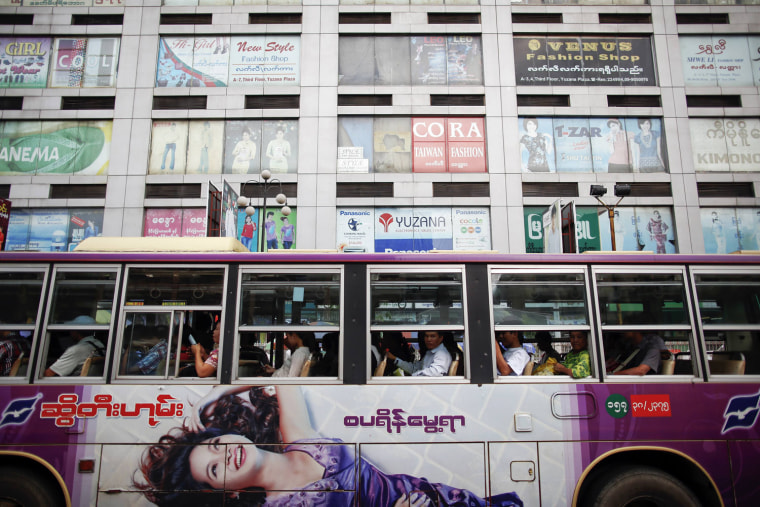 Passengers wait for a bus to leave a station in front of a shopping mall in central Yangon, Sept. 23.