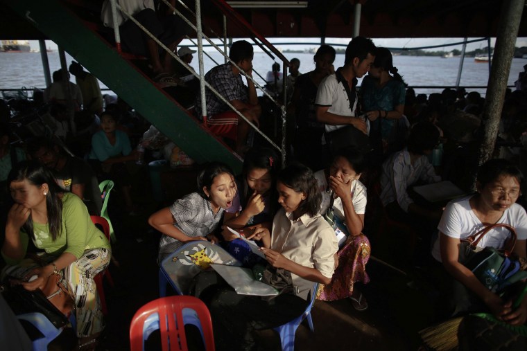 Schoolgirls read a letter as they sit among other passengers travelling on a government-owned ferry to Dallah Township, Sept. 18. Thousands of daily migrants cross the river to Dallah using dangerous long tail boats and cheap government operated ferries.