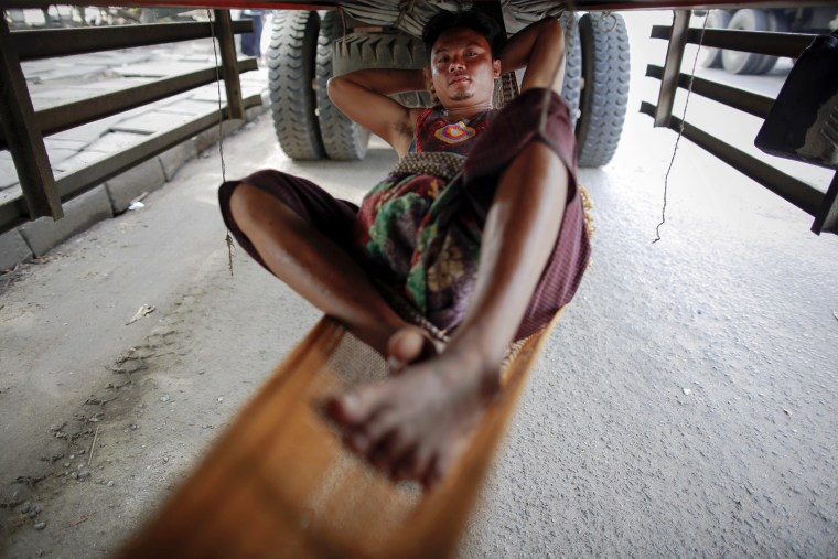 A driver rests in a hammock under his truck parked in central Yangon, Sept. 19.