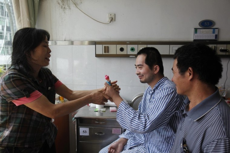 Zhang Tingzhen (center) is given a doll to play with by his mother Wei Xiuying while sitting beside his father Zhang Guangde at a Shenzhen hospital in southern China Sept. 26.